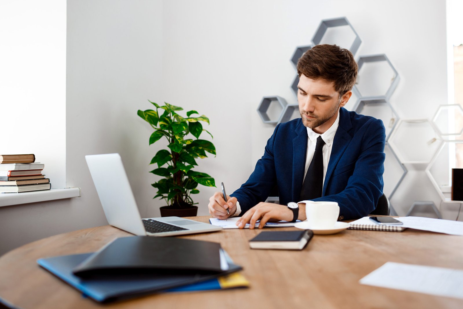 young successful businessman sitting at workplace, office background.